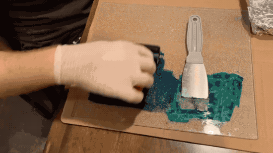 A video showing the process of applying ink to a printing plate with a roller, putting a card on the plate, pressing down on the paper, and eventually removing it showing the image on the paper.